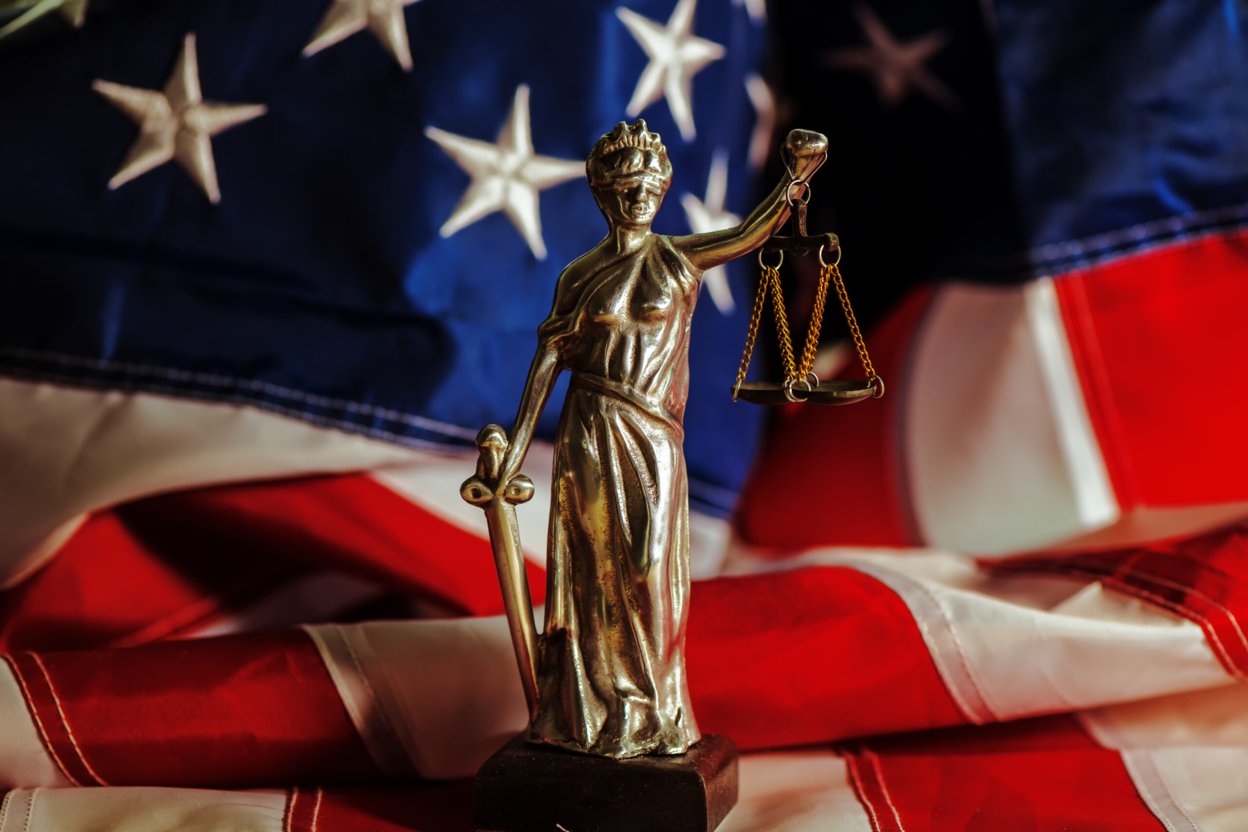Law and Justice in United States of America, statue of Lady Justice with USA flag in background, selective focus