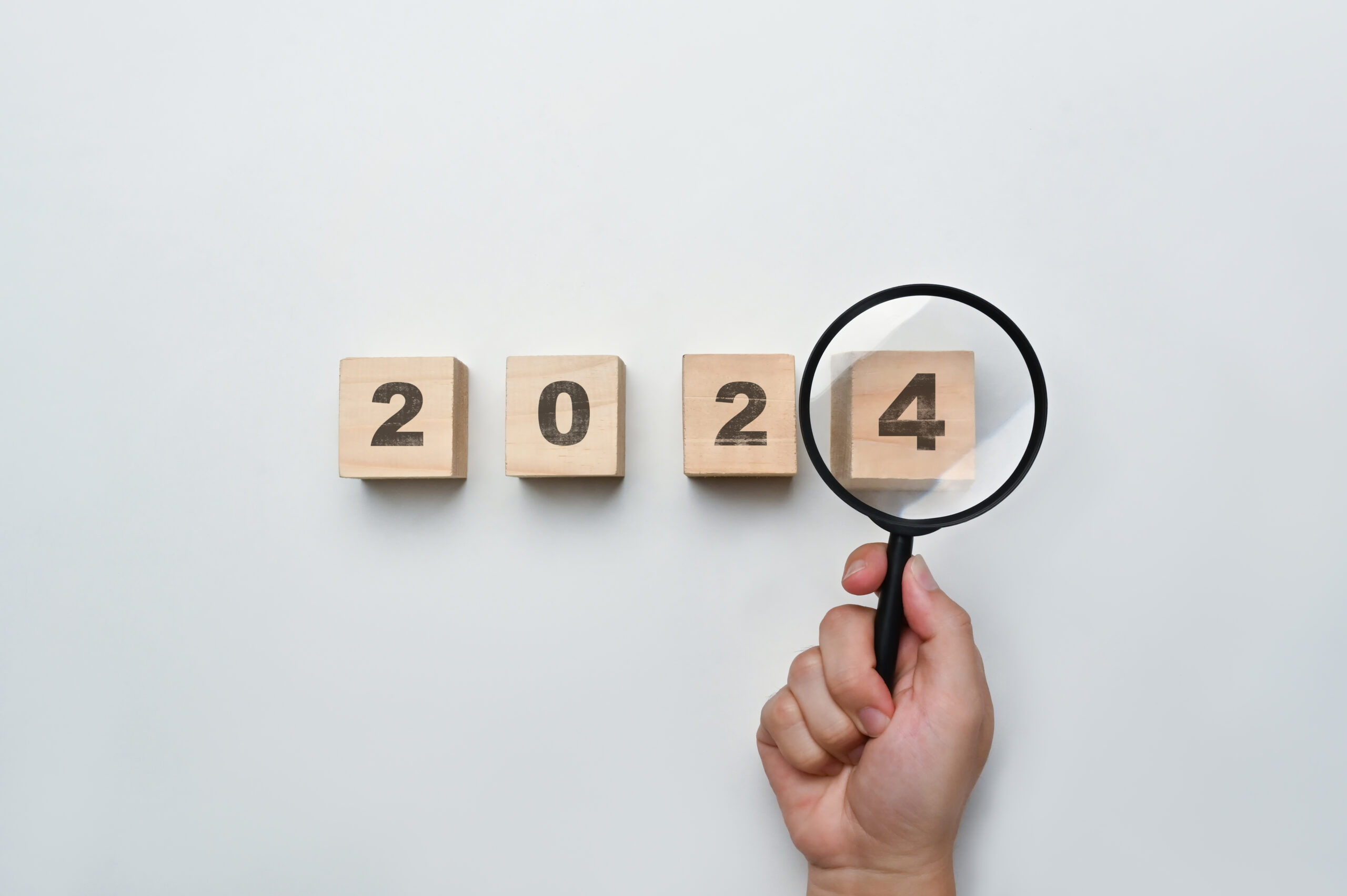 Magnifying glass and wooden cubes with 2024 year number on white background